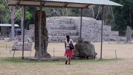 female tourist approaches ancient carved stele stone at copan maya ruin