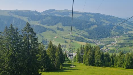 view from a slow chairlift descending toward schwarzsee lake and the rolling hills of the alpine swiss landscape on a sunny spring day