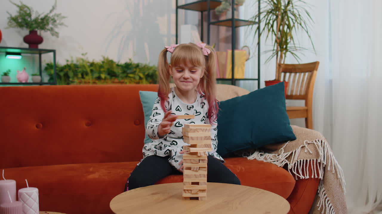 una niña adolescente feliz jugando a bloques de torre de madera juego de ladrillos en casa en la sala de estar moderna