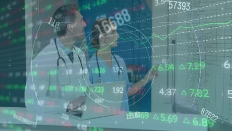 animation of stock market data processing on caucasian male and female doctor discussing at hospital