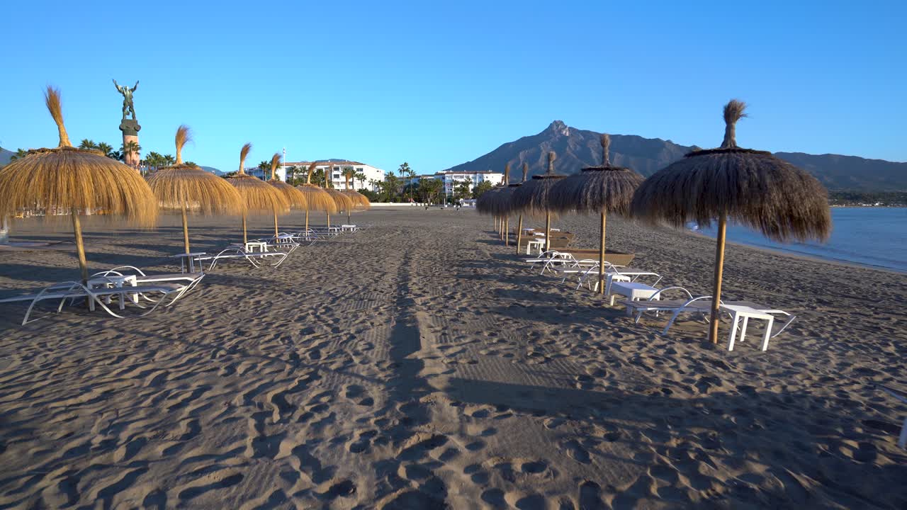 Marbella beach stable gimbal shot gliding backward between sunbeds and umbrellas, luxury travel inspiration