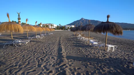 marbella beach stable gimbal shot gliding backward between sunbeds and umbrellas, luxury travel inspiration