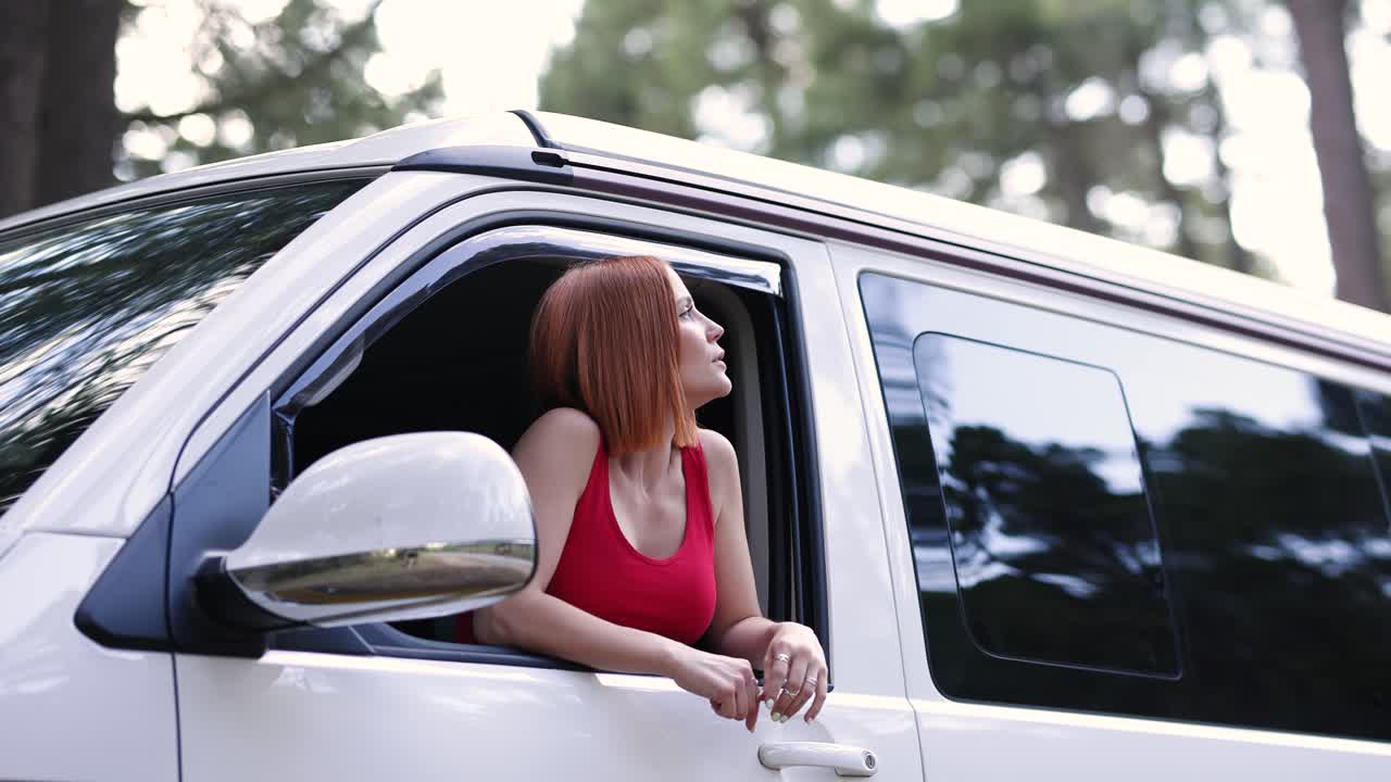 Giovane donna che guarda fuori dal finestrino dell'auto durante un viaggio