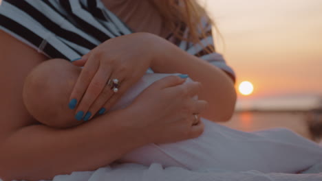 mother breastfeeding baby outdoor at sunset
