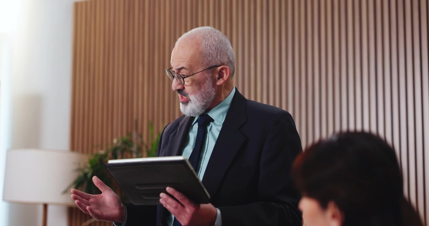 Uomo d'affari senior che presenta dati su tablet a un collega