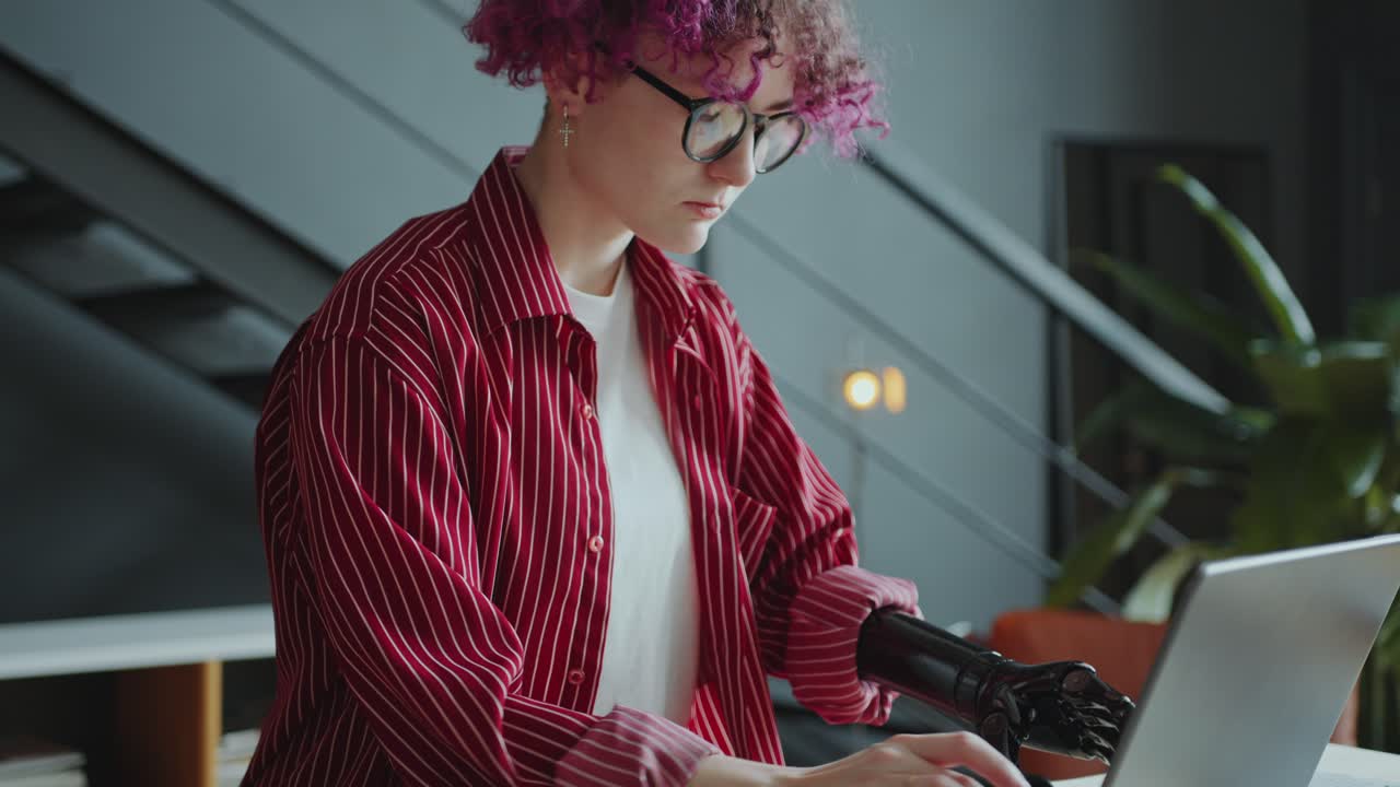 Girl with Prosthetic Arm Using Laptop and Taking Notes during Office Workday