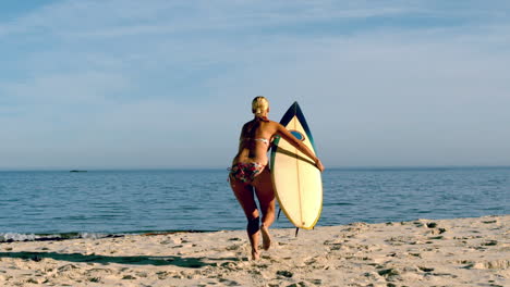 blonde surfer picking up board and running towards ocean