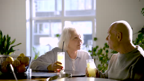 senior couple drinking limonade and talking while they are sitting in a bar at sunset