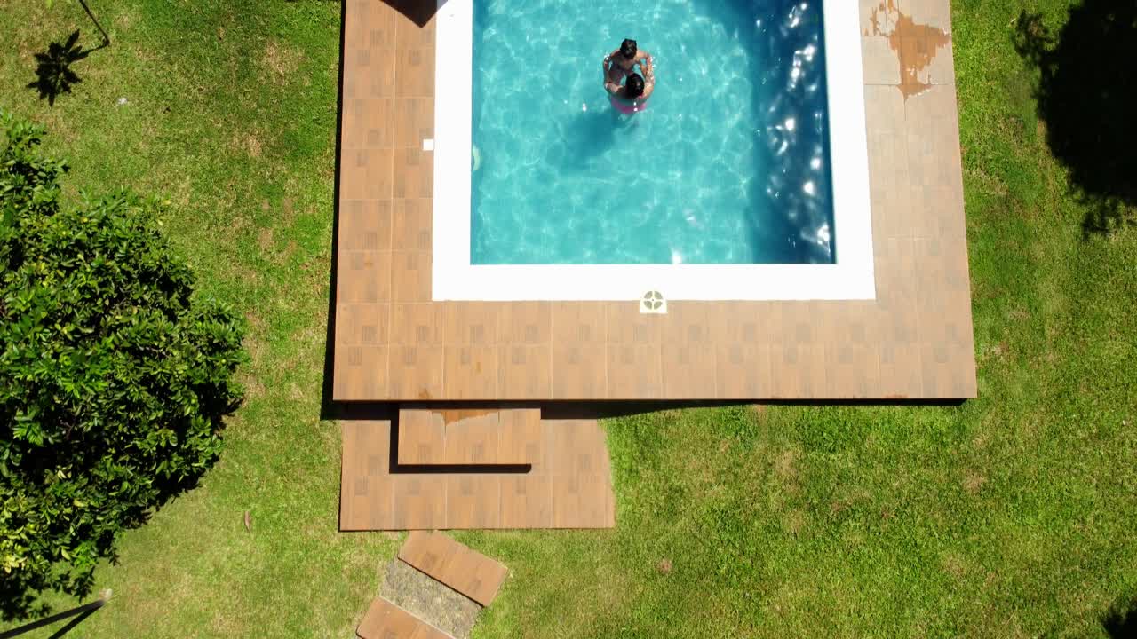 Ovenfra-optagelse af mor og søn, der nyder varmt vand i et imponerende pool-design.