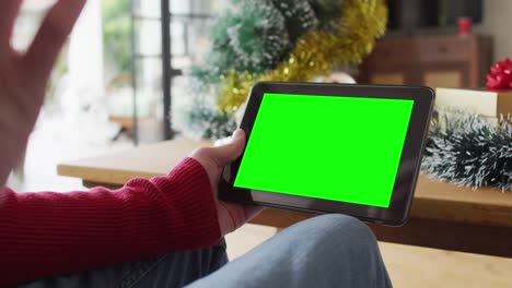 hombre caucásico en sombrero de santa haciendo llamada de video de navidad de tableta, con pantalla verde