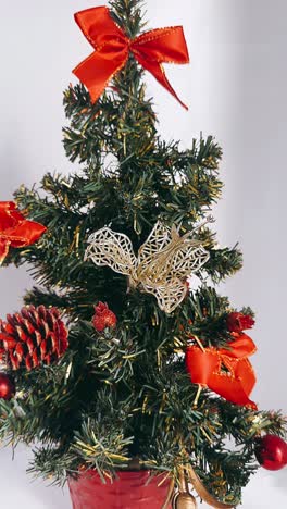 pequeño árbol de navidad con cinta roja y adornos de oro