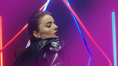 close up view of brunette woman dancing looking at camera in futuristic room with neon lamps