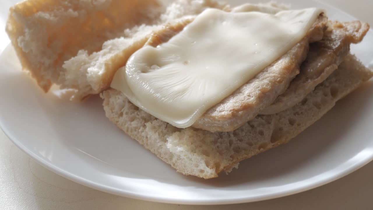 Bocadillo pork tenderloin sandwich with melted cheese on a white plate