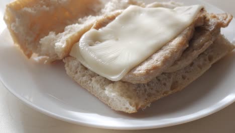 bocadillo pork tenderloin sandwich with melted cheese on a white plate