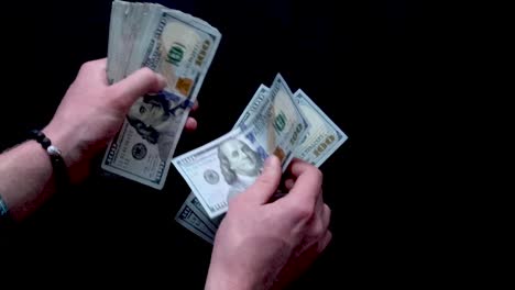 Counting-down-one-hundred-dollar-bills-onto-a-black-surface-in-slow-motion