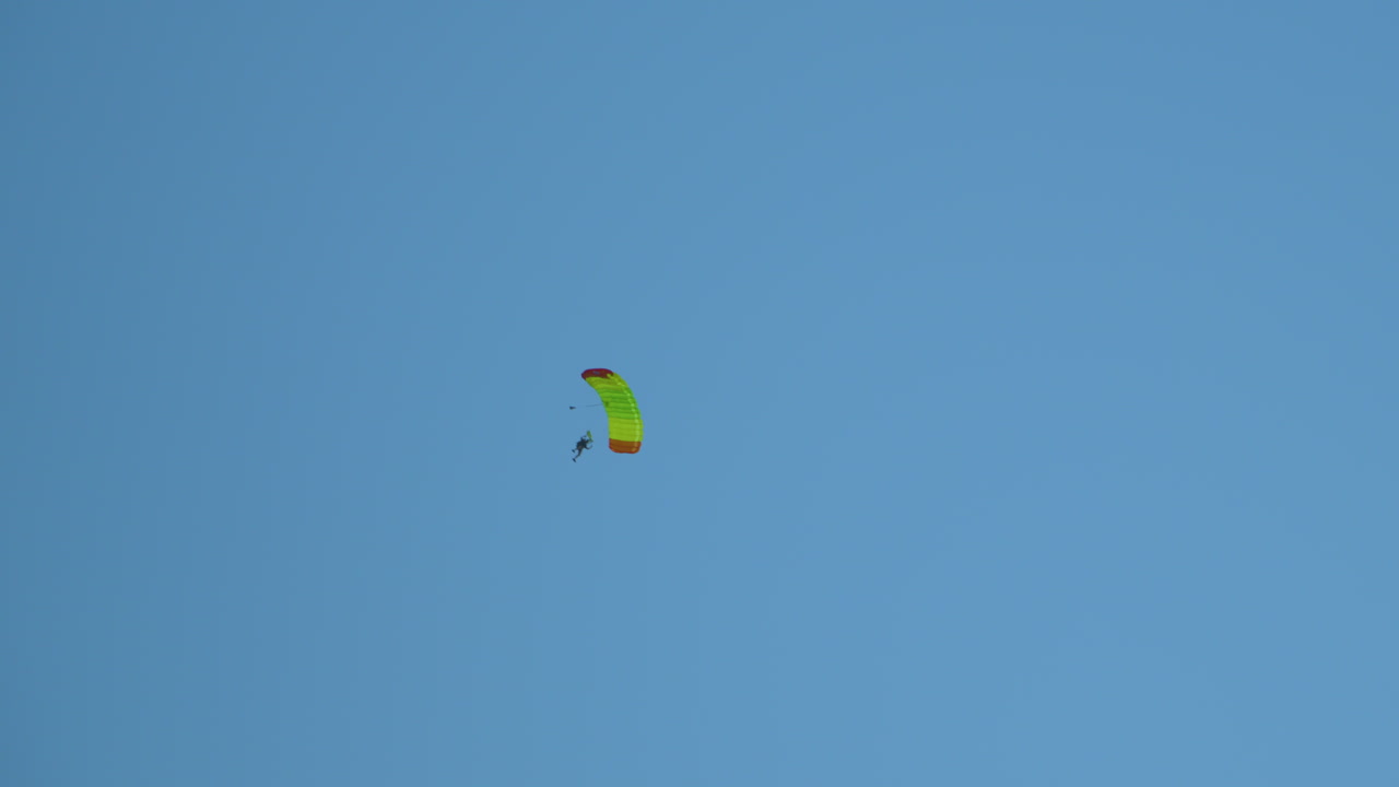 paracaidista hombre persona que se desliza en un paracaídas abierto para un descenso controlado en un cielo azul