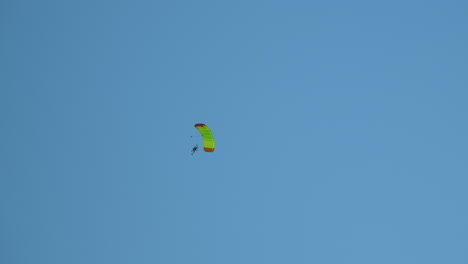 skydiver man person gliding on an opened parachute for a controlled descent in a blue sky