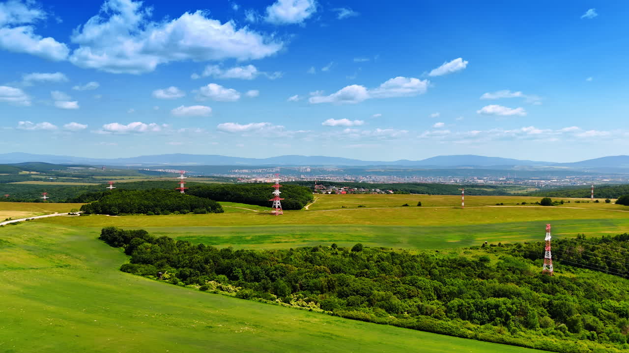 Green landscape with towers. Vivid green fields stretch across the countryside, interrupted by red and white communication towers in the distance