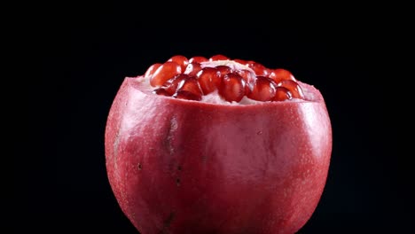 video of rotating red pomegranate seeds on black background