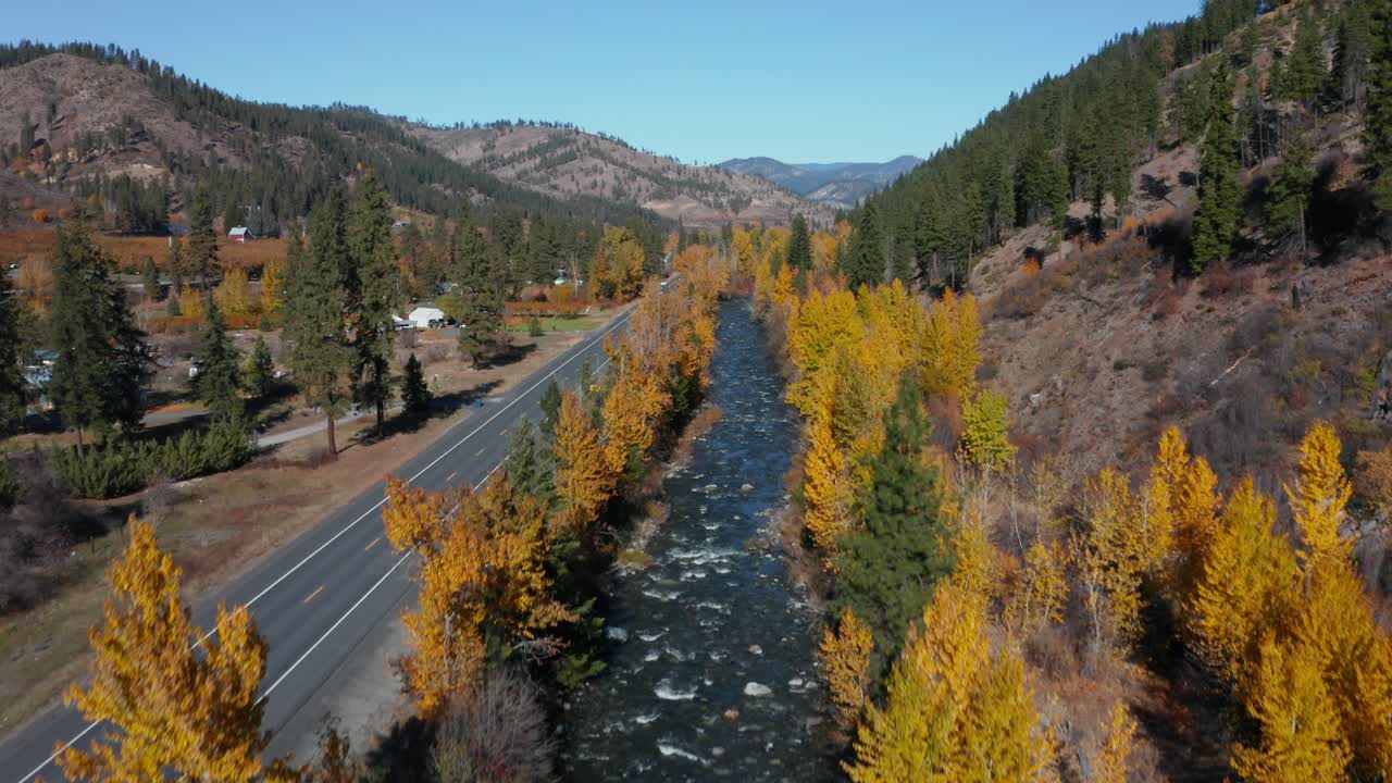 río salvaje que fluye rápido por la carretera cerca de un pequeño pueblo en washington, ee.uu.