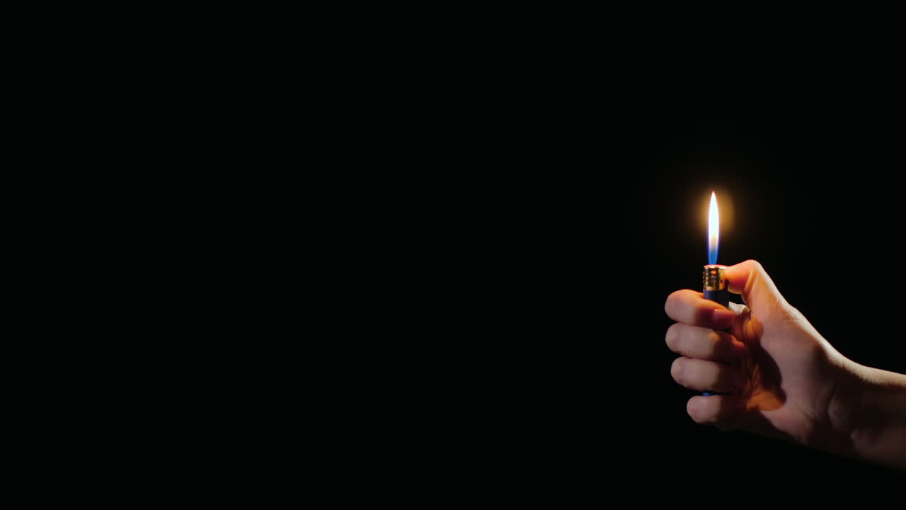 mano enciende llamas en un encendedor sobre fondo negro