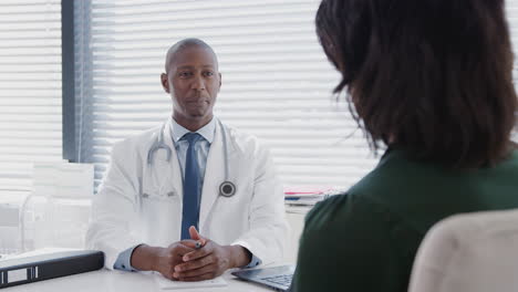 female patient shaking hands with doctor sitting at desk in office