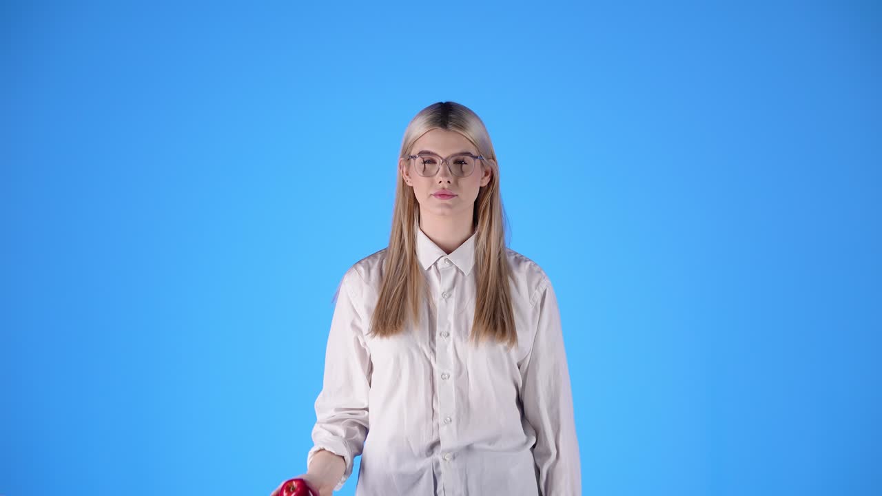 joven mujer caucásica juega lanzando una pelota en camisa blanca y gafas inteligentes rubia nórdica mujer hermosa, estudio profesional croma fondo azul, torso