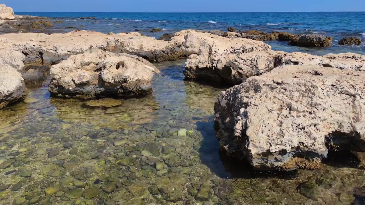 Acqua limpida e poco profonda e costa rocciosa in una giornata di sole