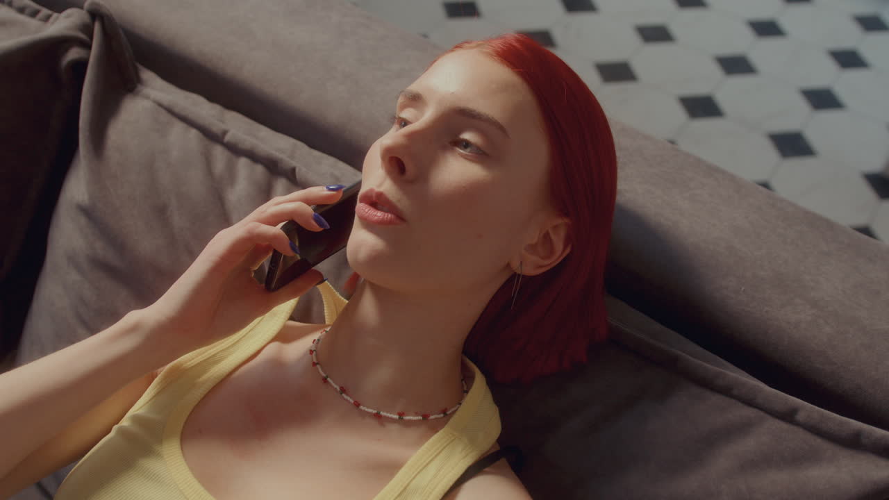 집에서 소파에 누워서 드폰으로 얘기하는 소녀