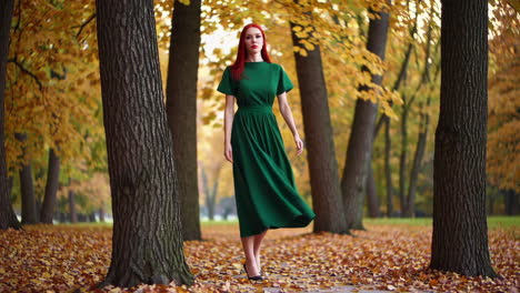 woman with red hair in green dress in an autumn park
