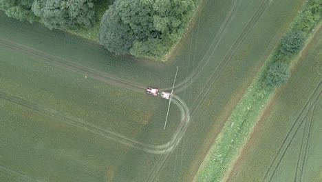 4k aerial footage of tractor spraying crops on a farm in england