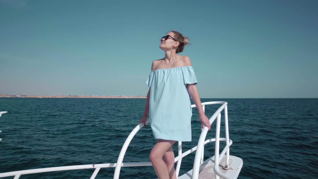 파란색 드레스와 선글라스를 입고 요트에 탑승한 젊은 섹시한 카우카스 여성의 초상화 - 휴가, 자유, 빛 여름의 개념 - 배경에 파란 바다