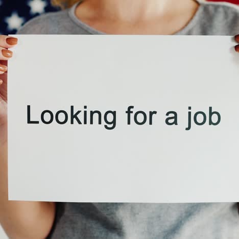 a woman holds a poster that says looking for a job