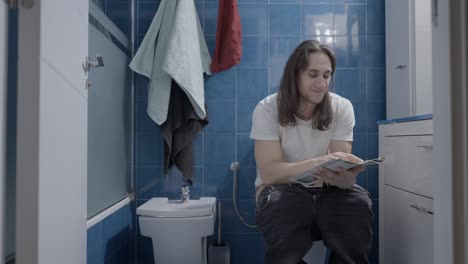 man reading a magazine on the toilet
