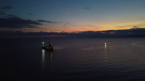 aerial of boat, oil tanker at dusk, parked in the ocean, unloading