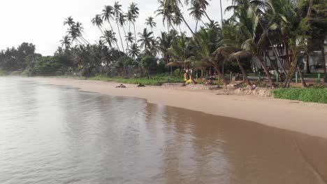 drone flying low over sandy shore of hiriketiya beach in sri lanka