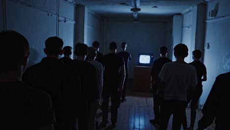 crowd watching a distorted image on an old tv in a dark corridor