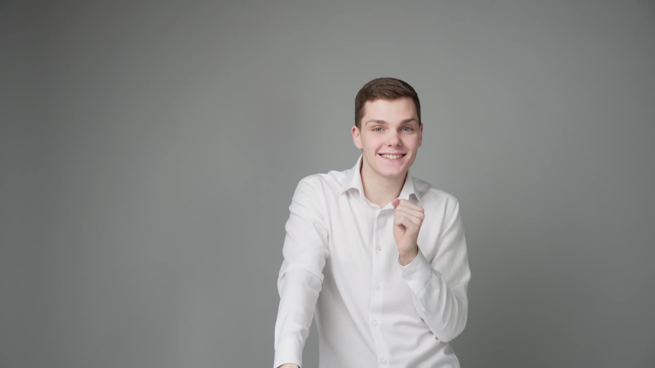 un joven bailando con una camisa blanca.