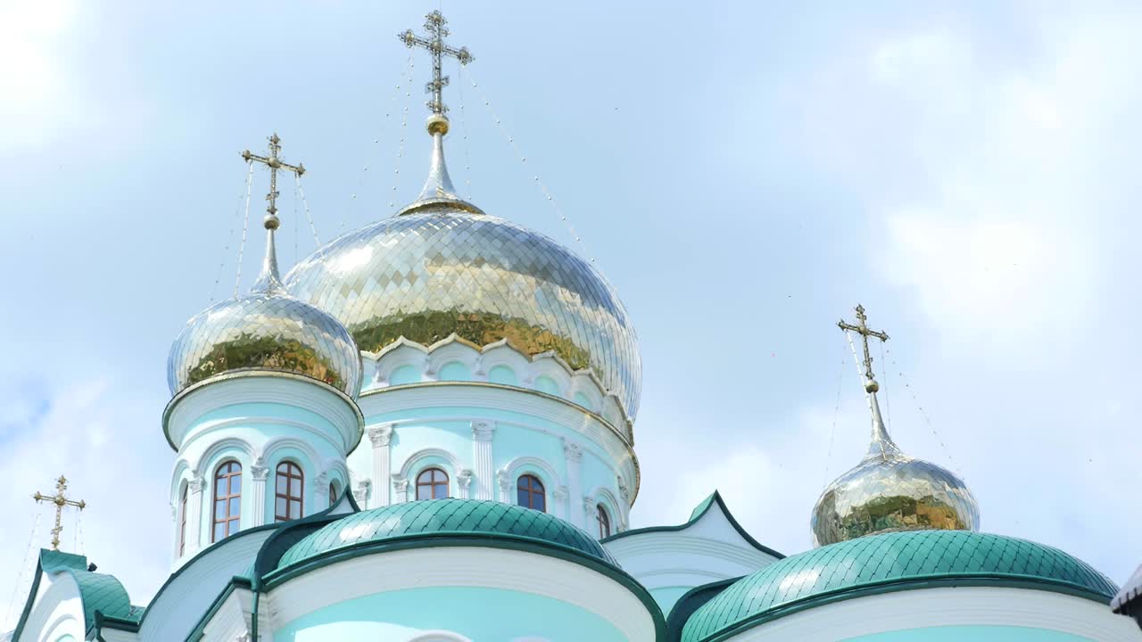 Восточные православные кресты на золотых куполах на фоне голубого облачного неба