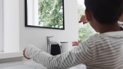 happy biracial brother and sister brushing teeth in sunny bathroom, slow motion