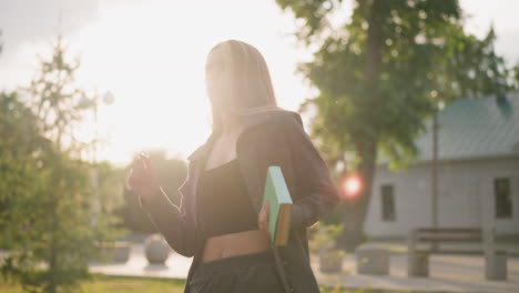 lady joyfully spins outdoors in grassy field with a book in hand, sunlight radiating around her, creating a bright atmosphere, background features greenery, trees, and a slightly blurred