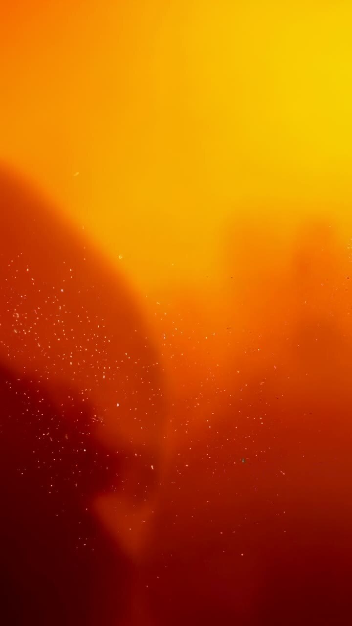 Vertical video: Playback starting orange-red haze drifting in warm mist with tiny bright flecks