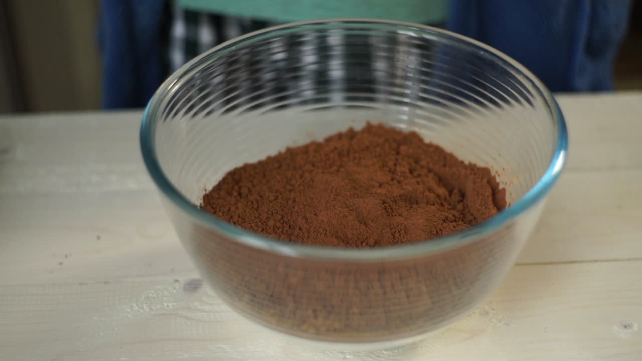 셰프는 코코아와 함께 유리 그 ⁇ 에 달 ⁇ 을 부러뜨립니다. 베이킹 재료. 요리 음식