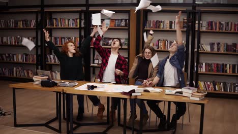 movimiento lento de los estudiantes que tiran las hojas de papel después de horas de estudio en la biblioteca de la universidad. estudiantes felices y libres que no quieren estudiar o están celebrando el comienzo de las vacaciones. felicitándose mutuamente por terminar los estudios