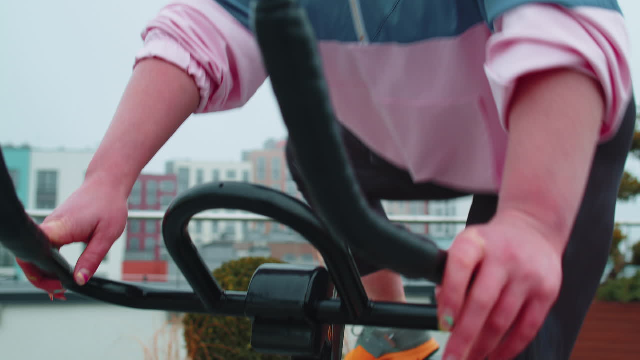 chica atlética realizando ejercicios de entrenamiento de equitación aeróbica en bicicleta bicicleta estacionaria en el techo de la casa