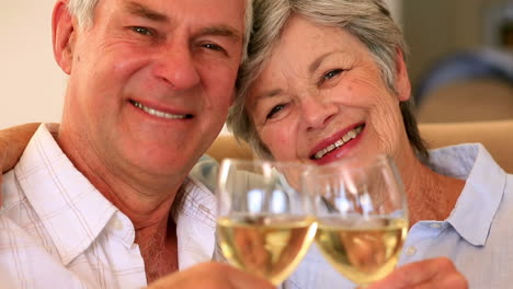 senior couple sitting on couch having white wine