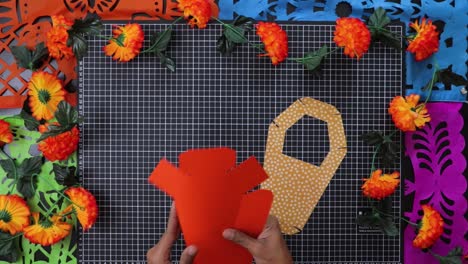 hands crafting vibrant day of the dead coffin box with bright cempasuchil flowers around