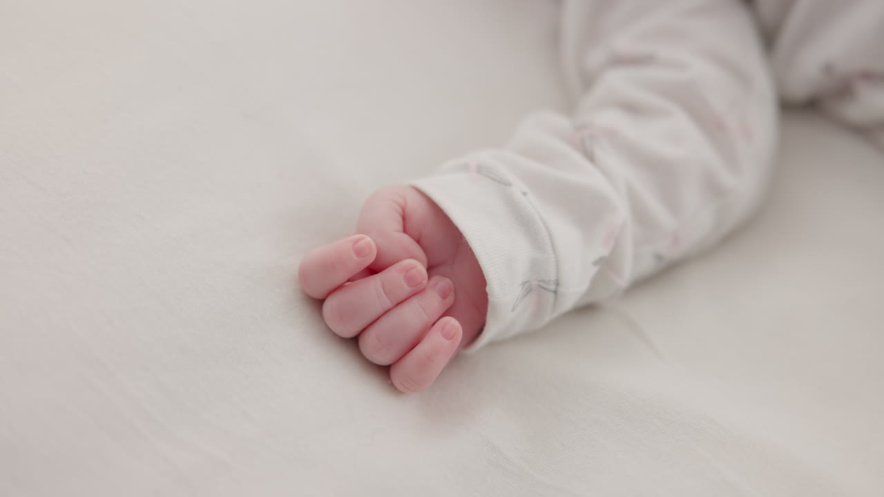 Hand, baby and sleeping on bed in nursery