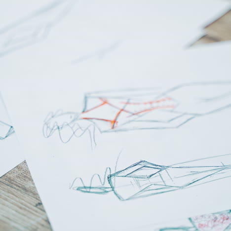 different stylish sketches of clothes on the sheets of papers lying on the table. a lot of creative works of a fashionable designer painted on papers.