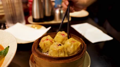 person enjoying dumplings with chopsticks at a restaurant